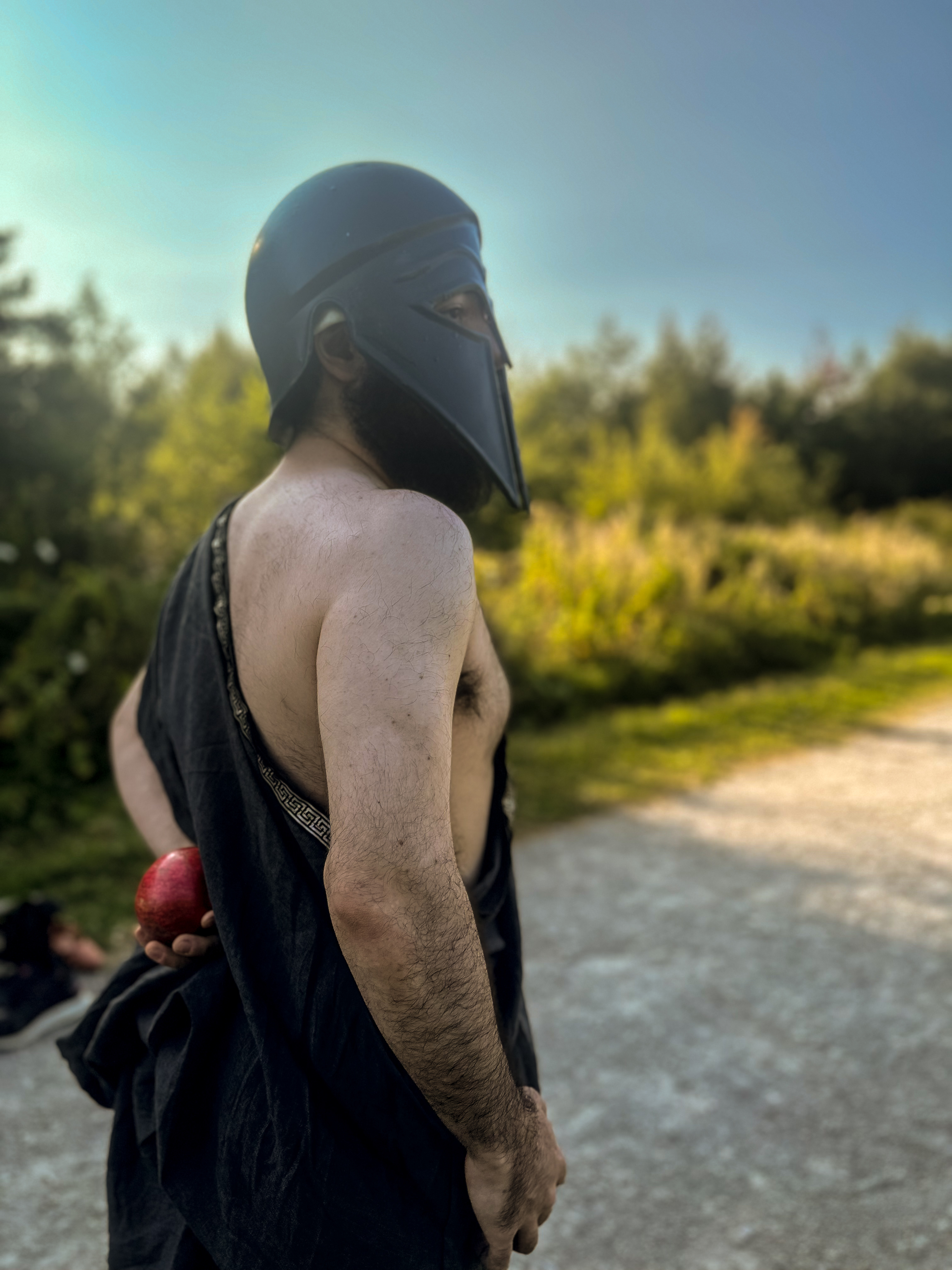 Hades glances away while holding a pomegranate behind his back